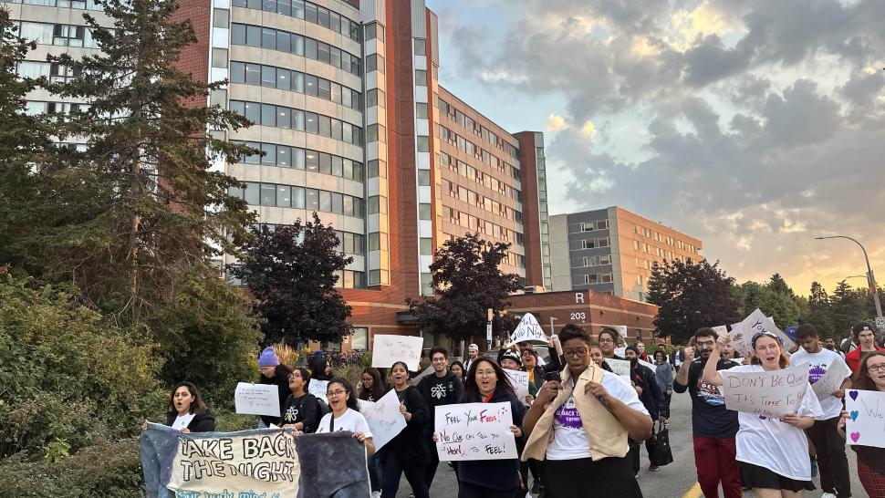 People march while holding signs that have writing on them including one that reads Take Back the Night.