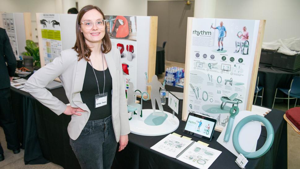 A person stands before a table that has a display on it that reads Rhythm.