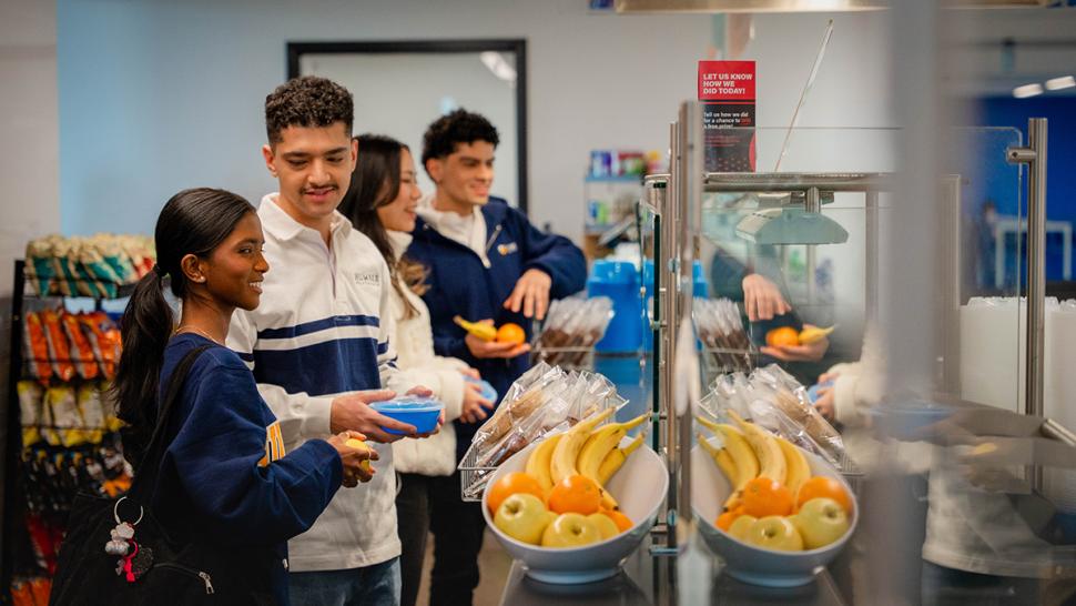 Students wait in line for food in a cafeteria.