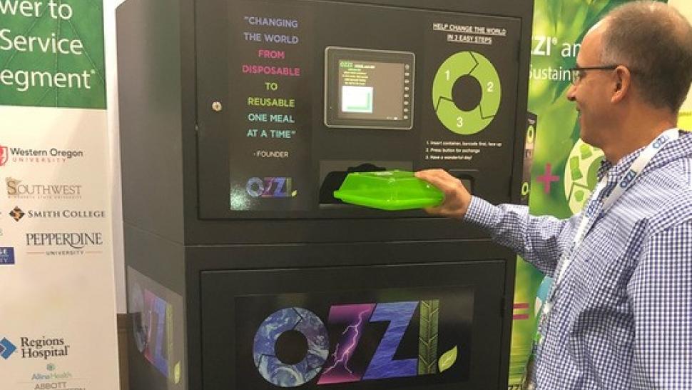 A person returns a reusable food container to a machine that collects them.