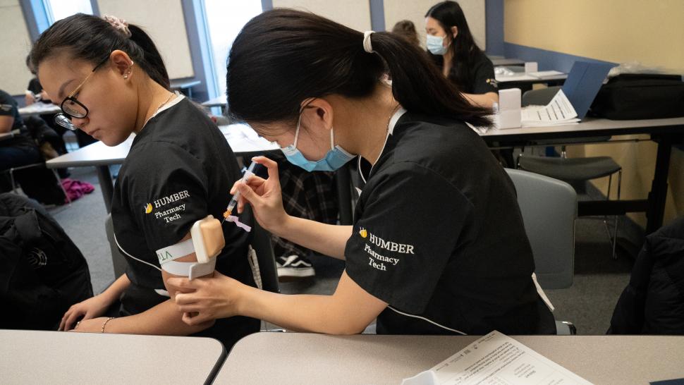 A Humber Pharmacy Technician student practices administering an injection on another student.