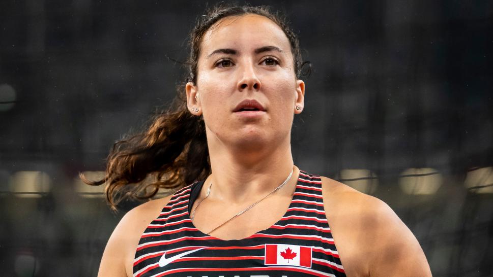 Renee Foessel looks into the distance with a discus in her hand with stadium seats in the background.