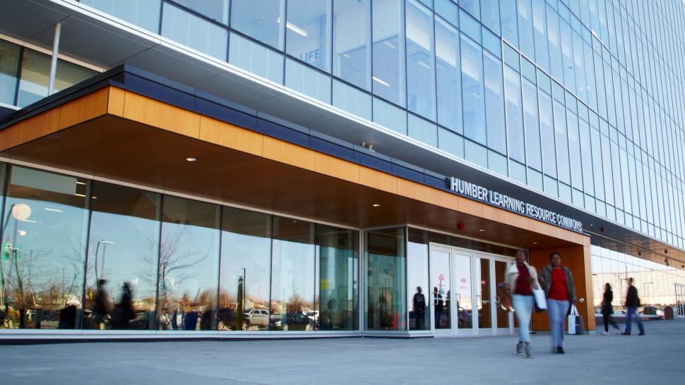 People walk outside a building that has a sign on it that reads Humber Learning Resource Commons.