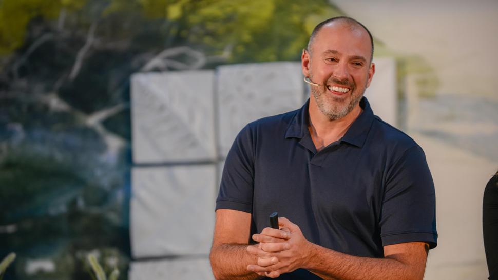 A smiling person wearing a headset and holding a device in their hand.