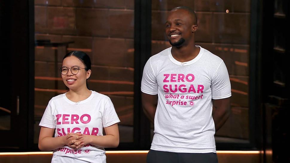 The Ambursleys on the set of Dragon's Den. They are smiling and wearing white t-shirts with the pink Oat Canada logo