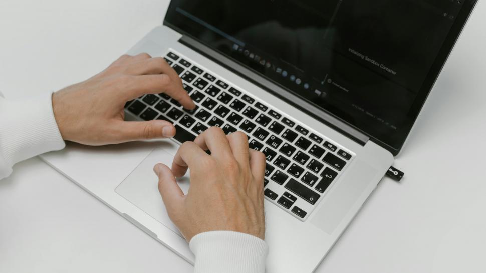 A pair of hands type on a laptop computer.