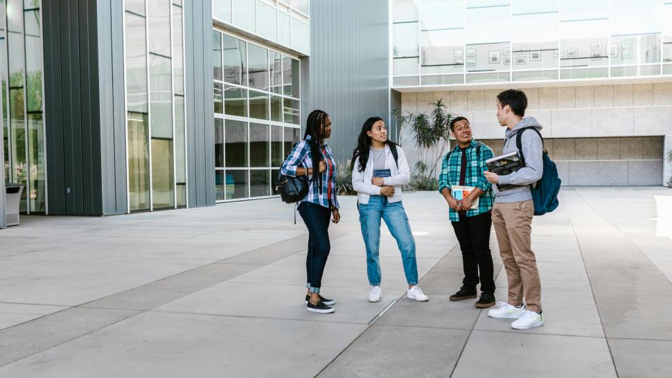 Four people talk as they stand outside a building.