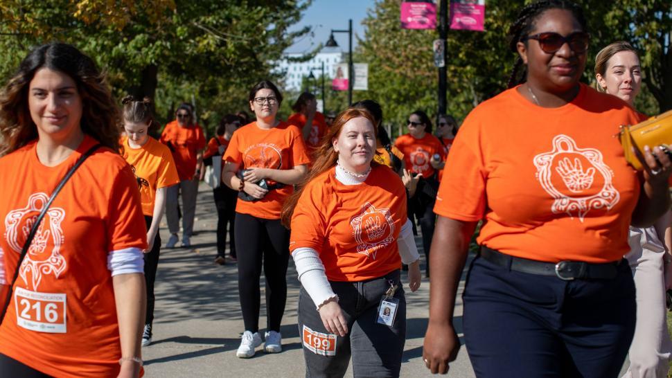 A group of people wearing orange shirts with designs on them are walking.