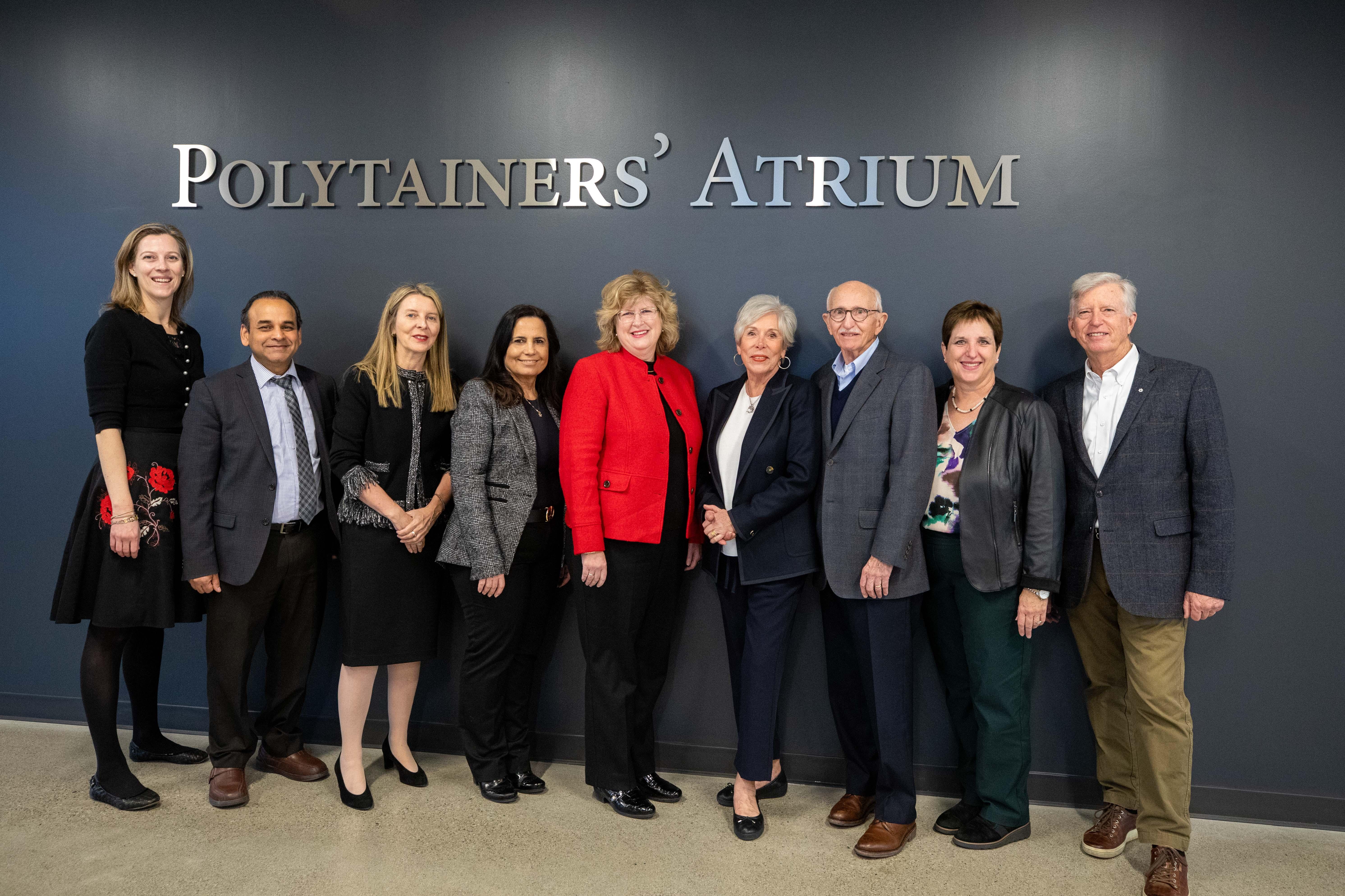 A group of people stand beneath a sign that reads Polytainers’ Atrium.