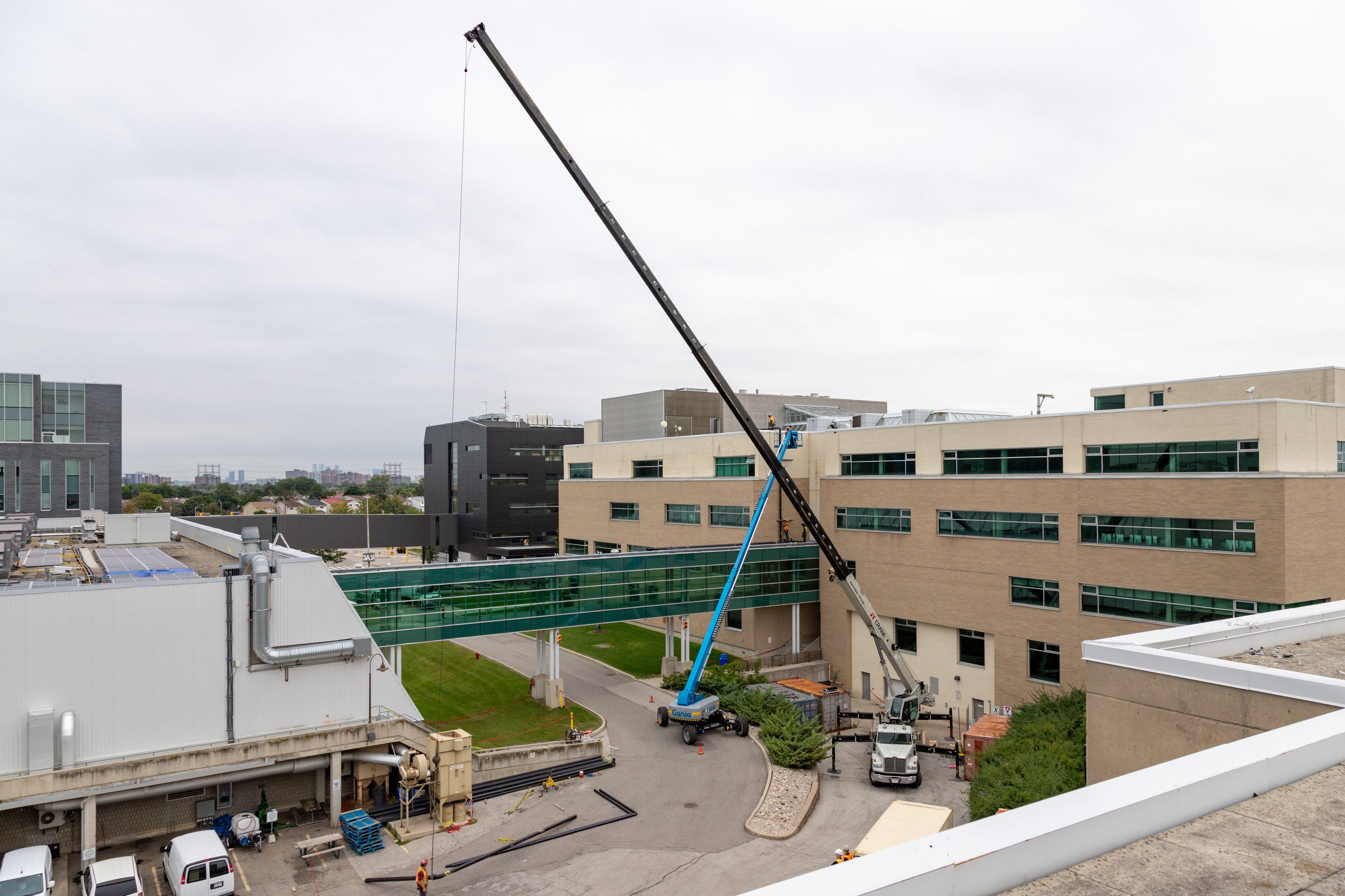 A crane prepares to lift a piece of pipe off the ground.