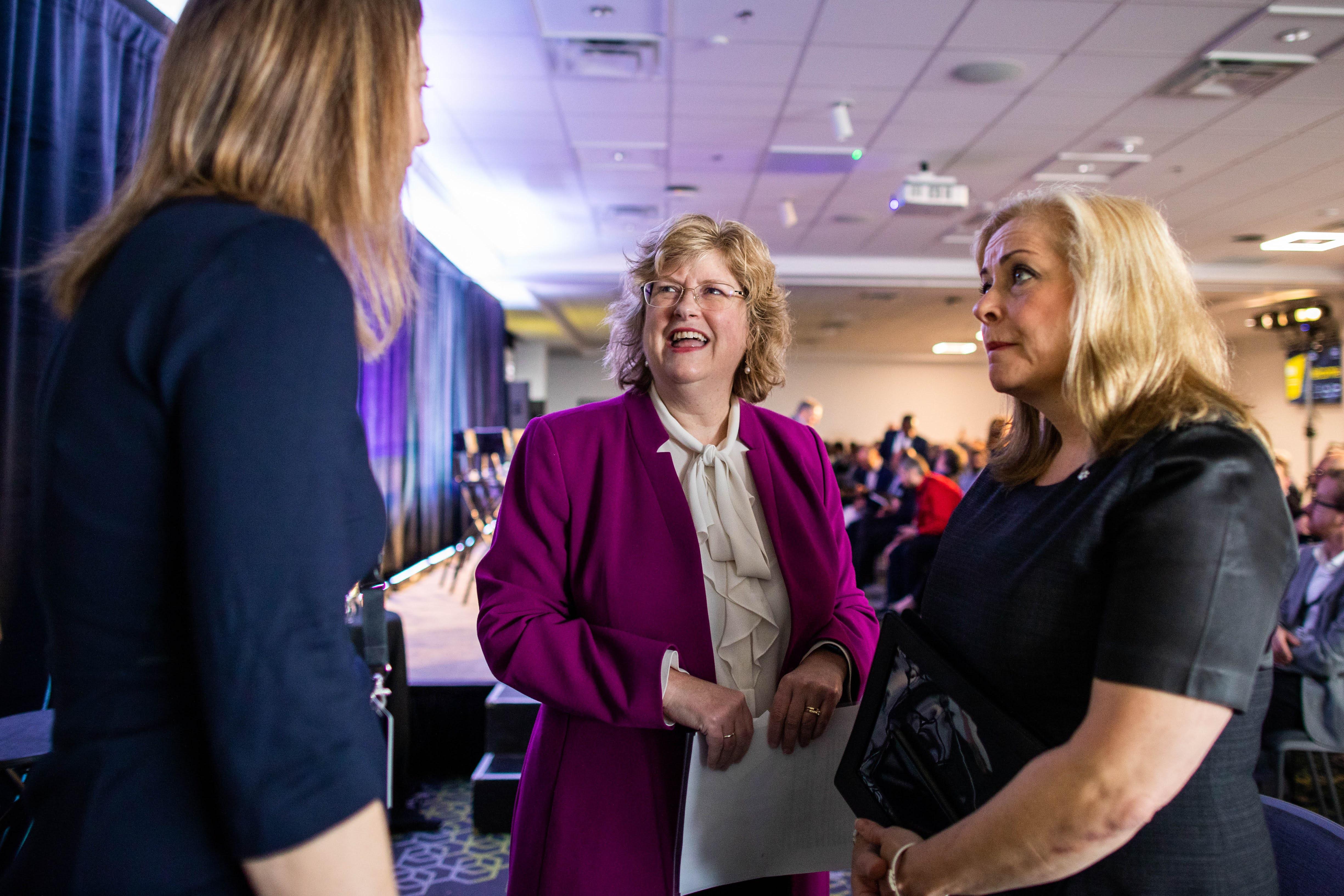 Two people have a discussion with Humber College President and CEO Dr. Ann Marie Vaughan.