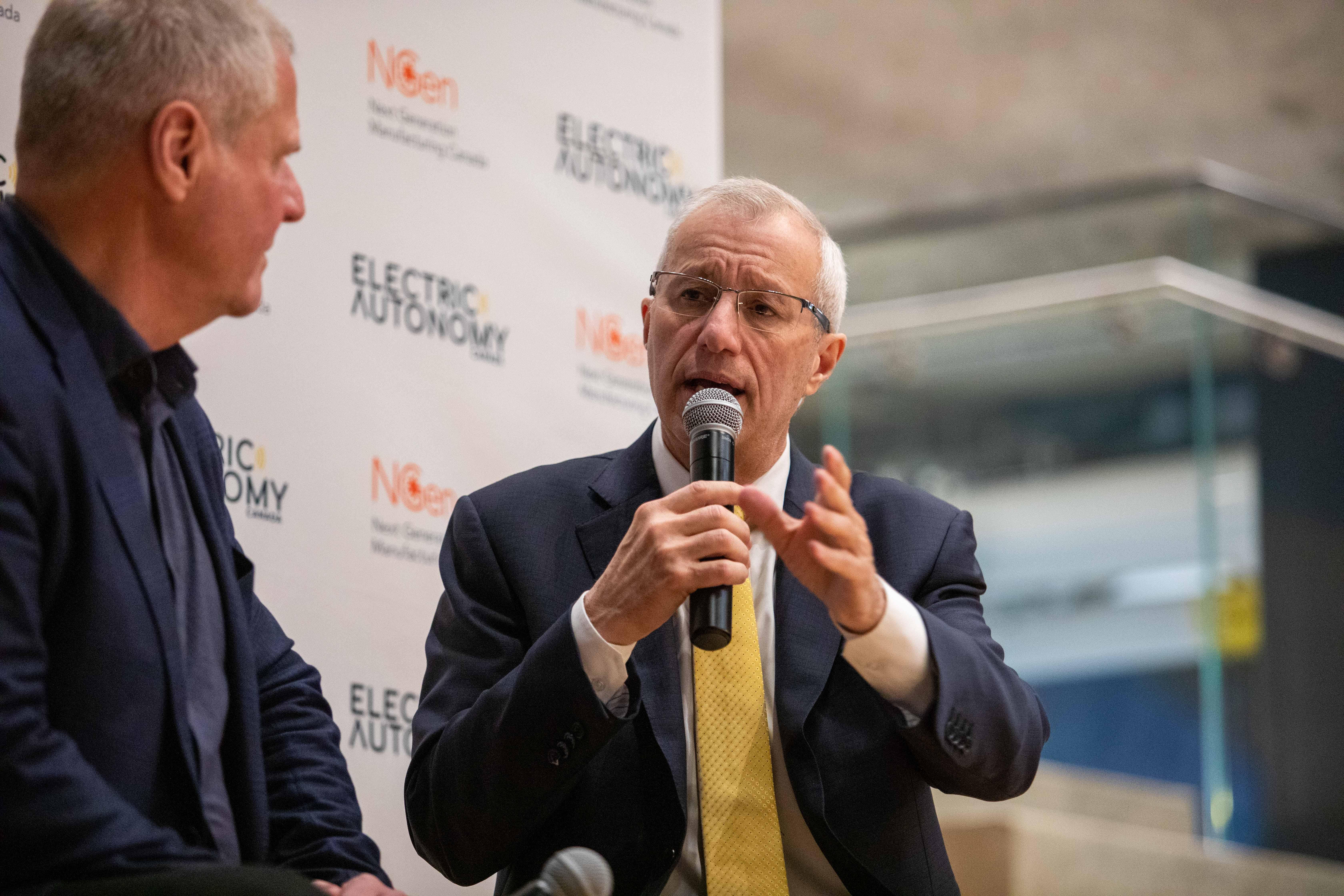 Two people have a discussion as one speaks into a microphone.