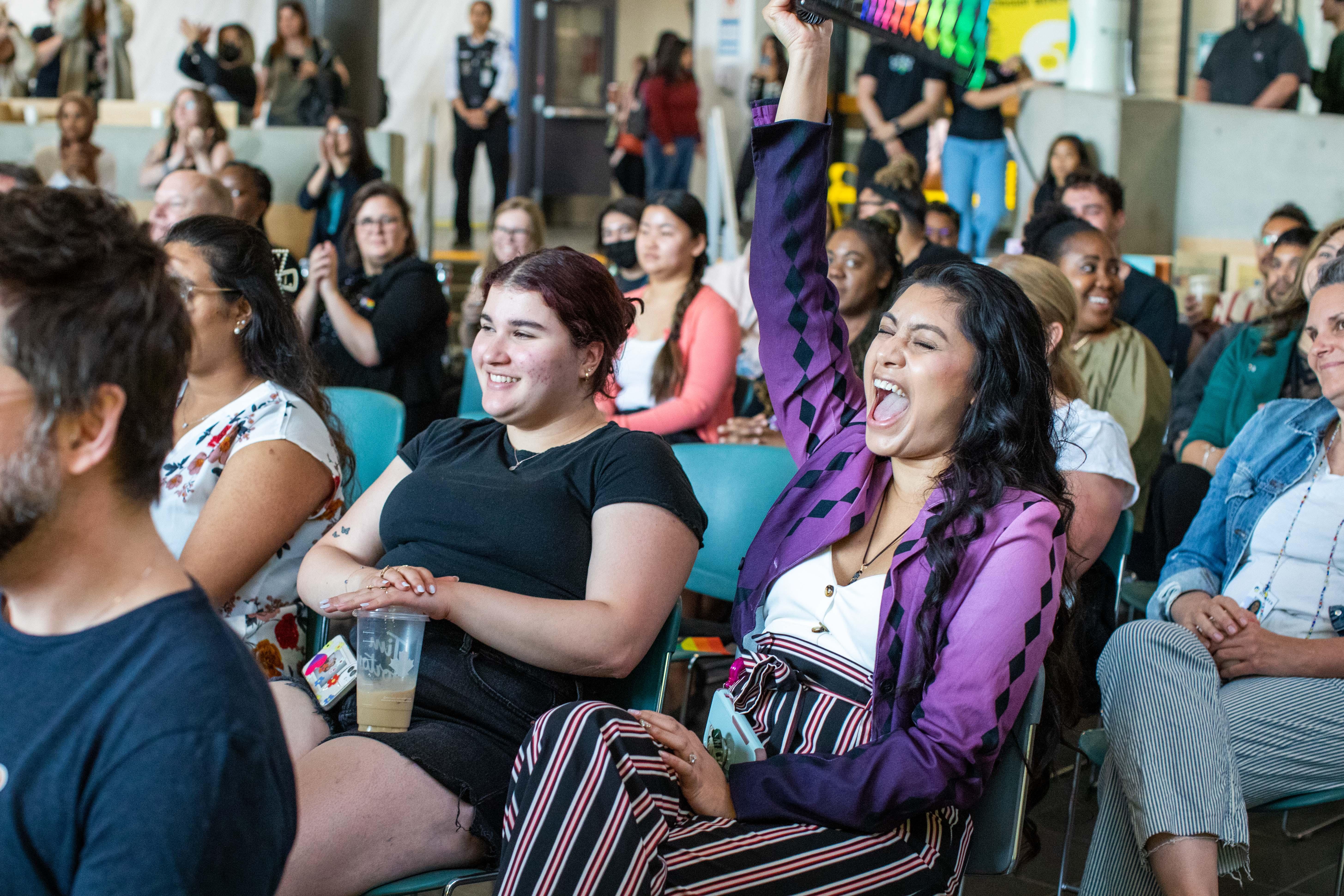 A person raises their arm in the air as they cheer. 