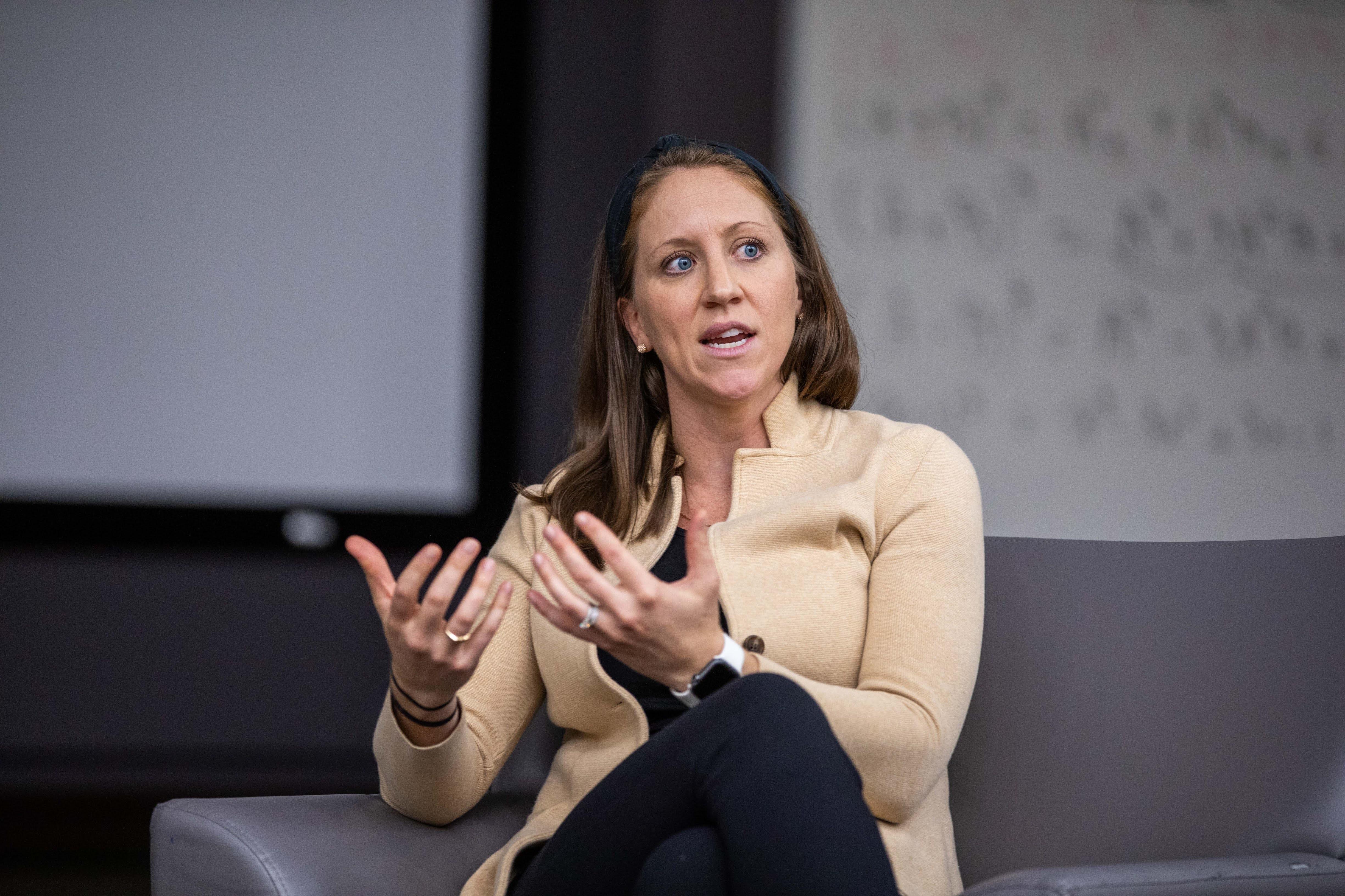 A person sitting in a chair speaks while moving their hands.