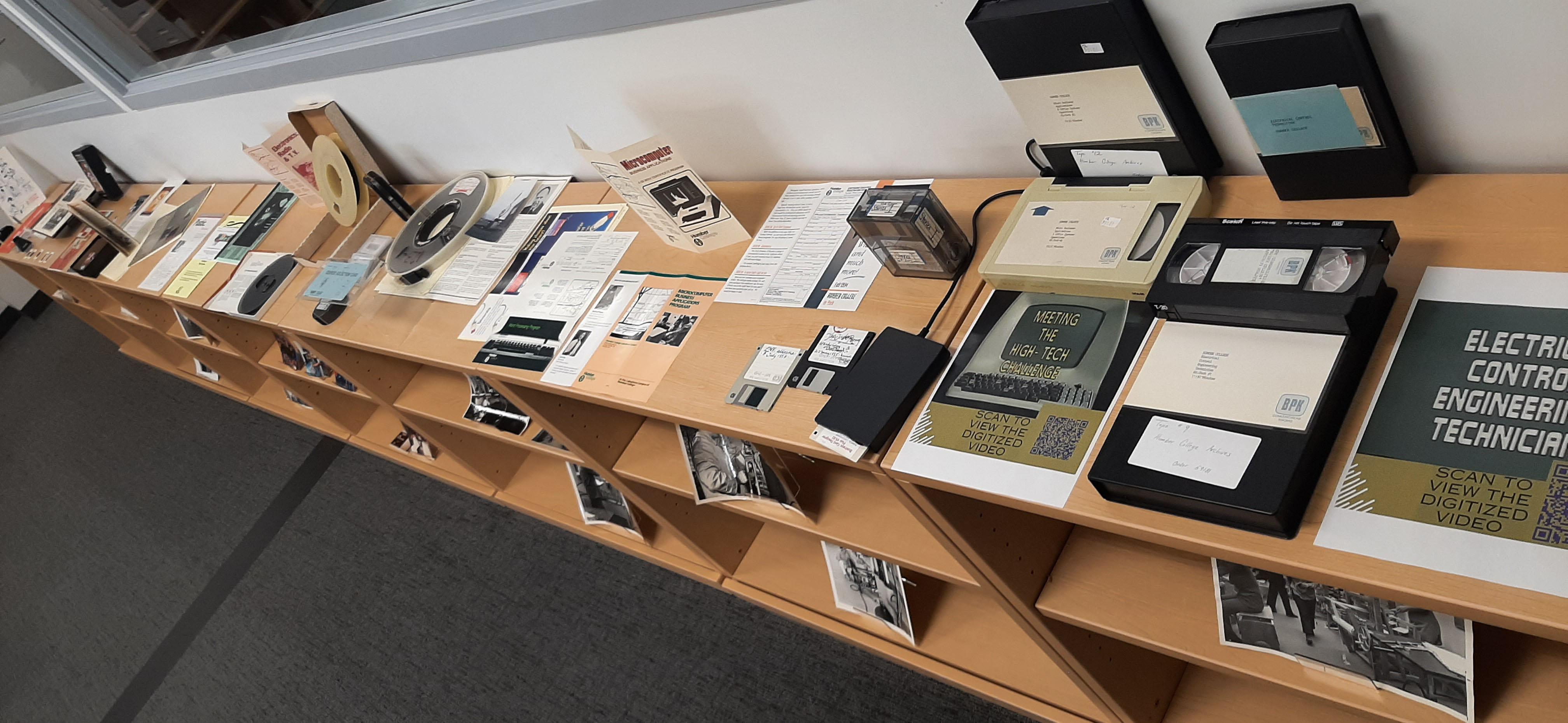 A collection of older media, including VHS tapes, and devices to play them sit on a table.