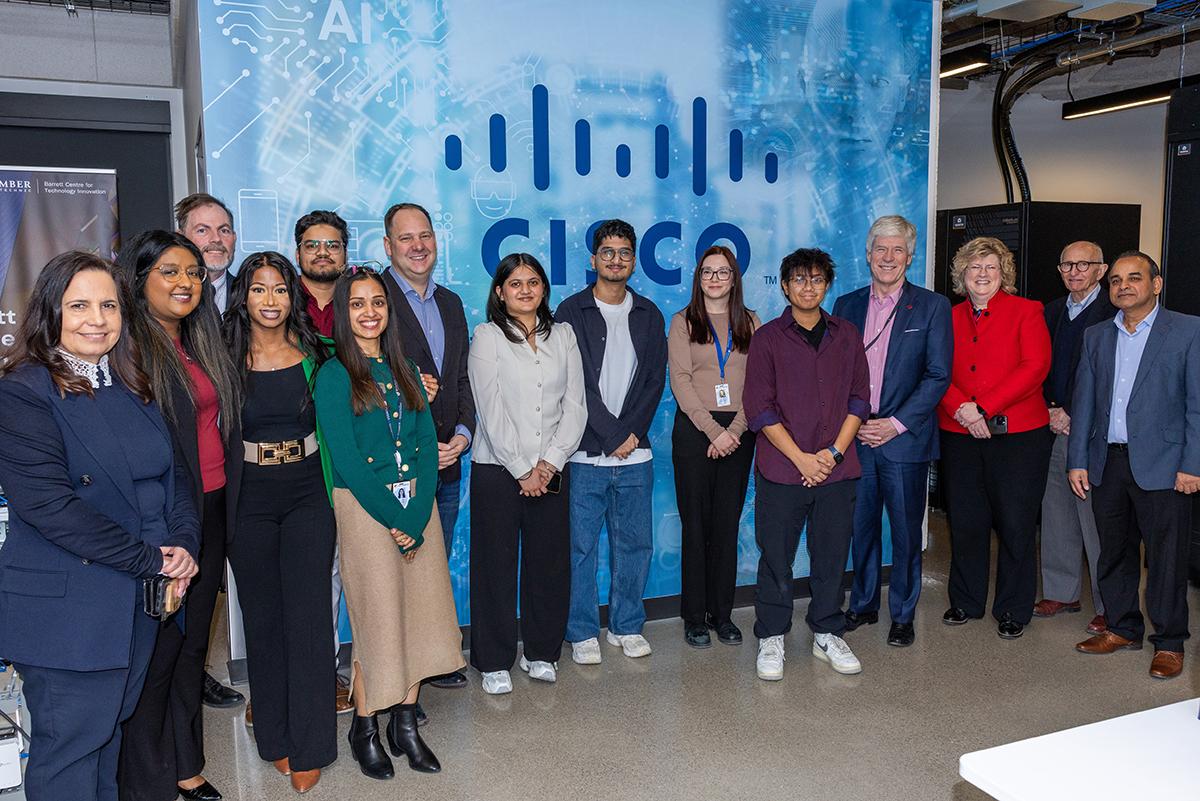 A group of people stand together in front of a CISCO sign.