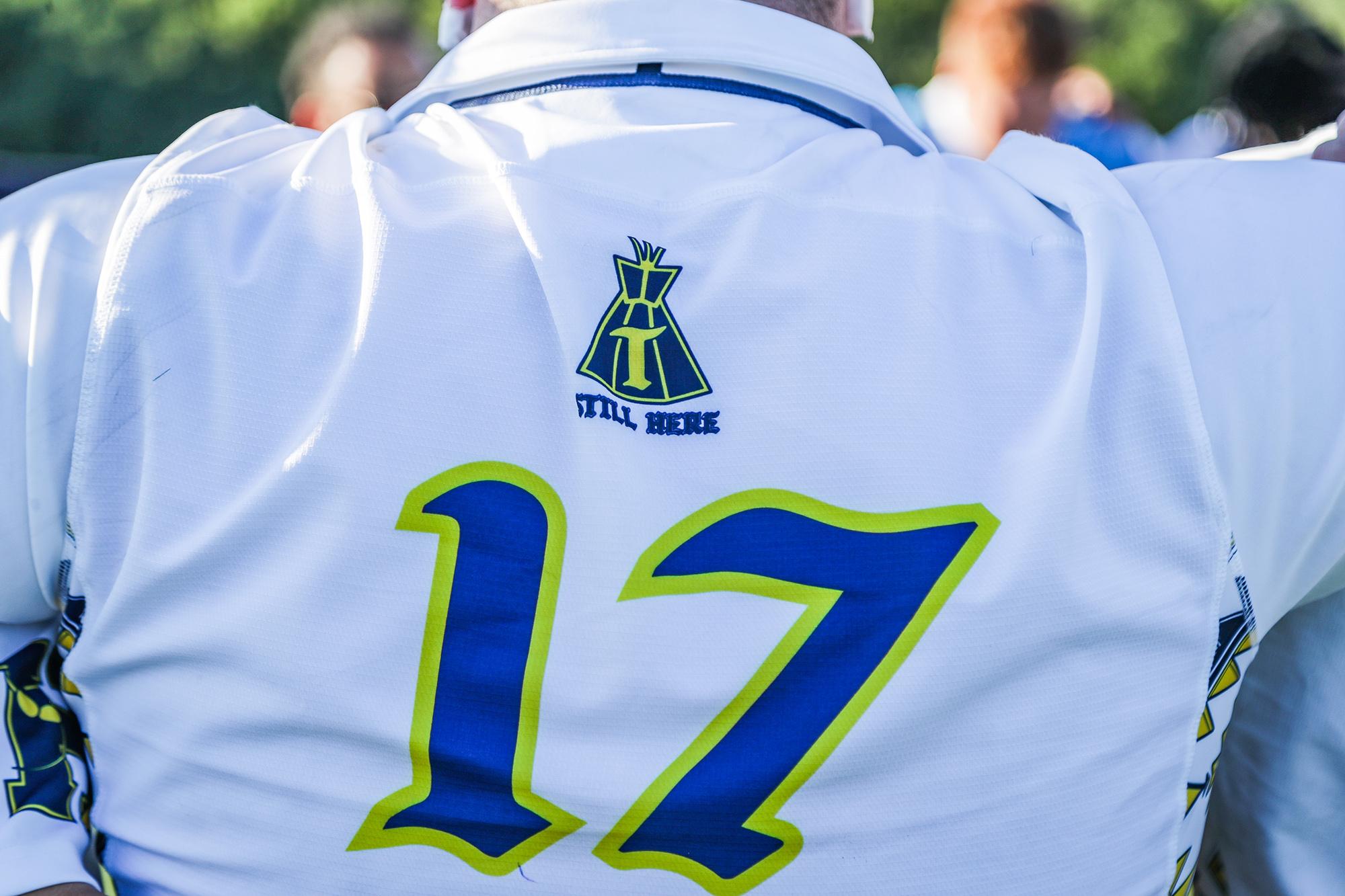 A closeup of the back of a jersey with the number 17 on it. There is a logo with the words Still Here below it.
