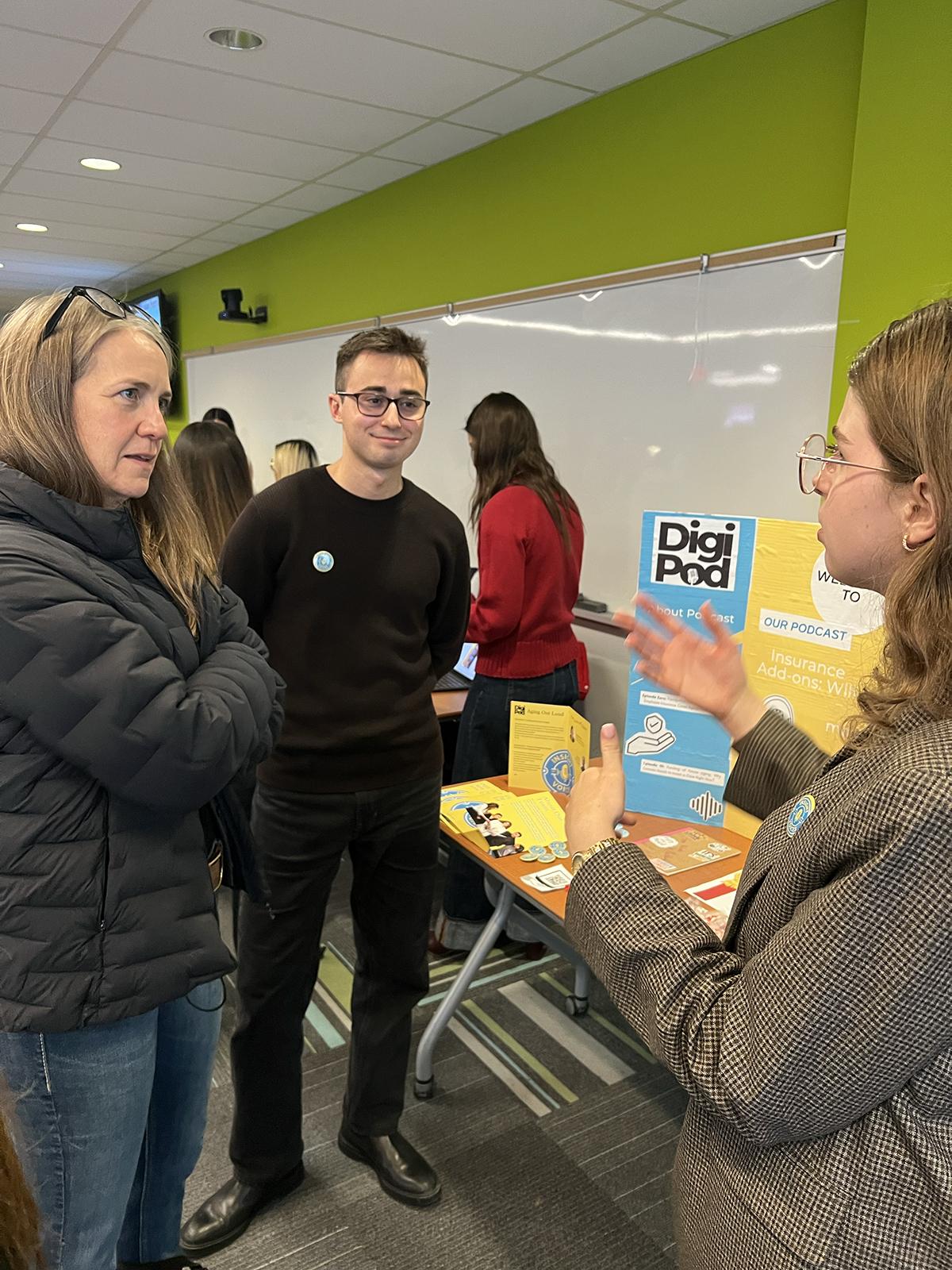 A person is speaking to two people who are listening intently.
