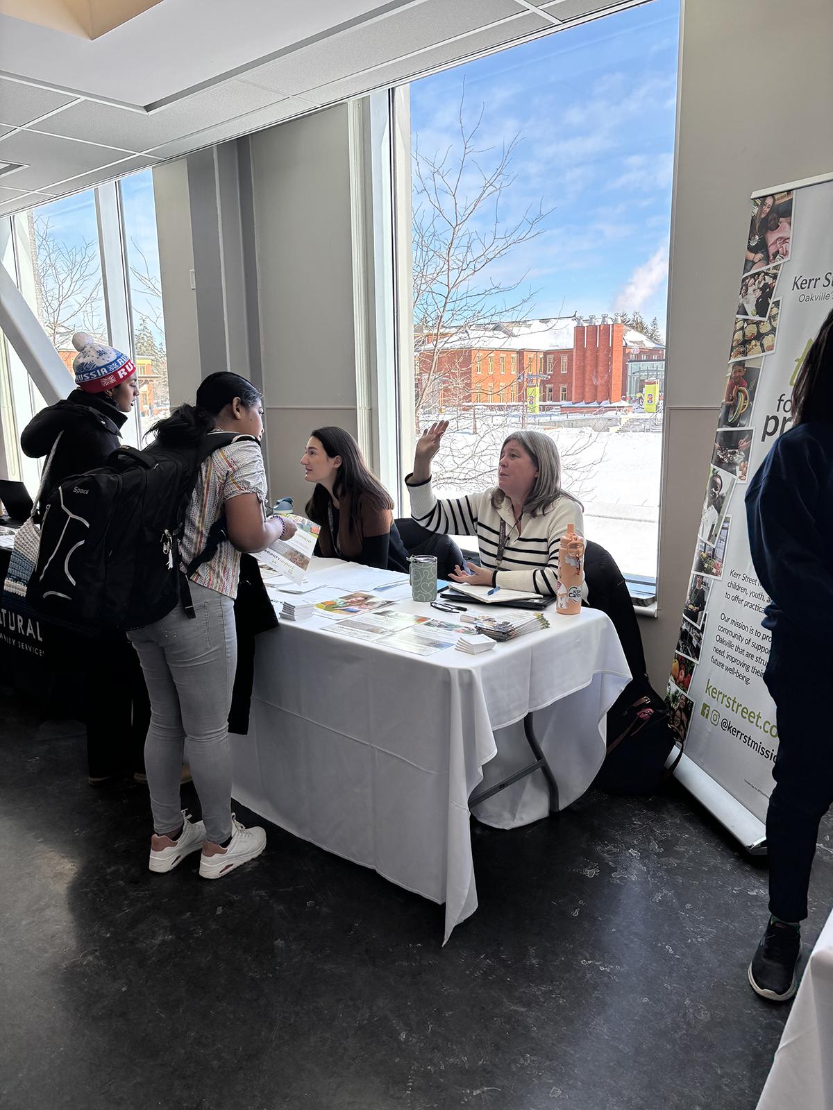 A person sitting at a table is having a conversation with another person who is standing in front of the table.