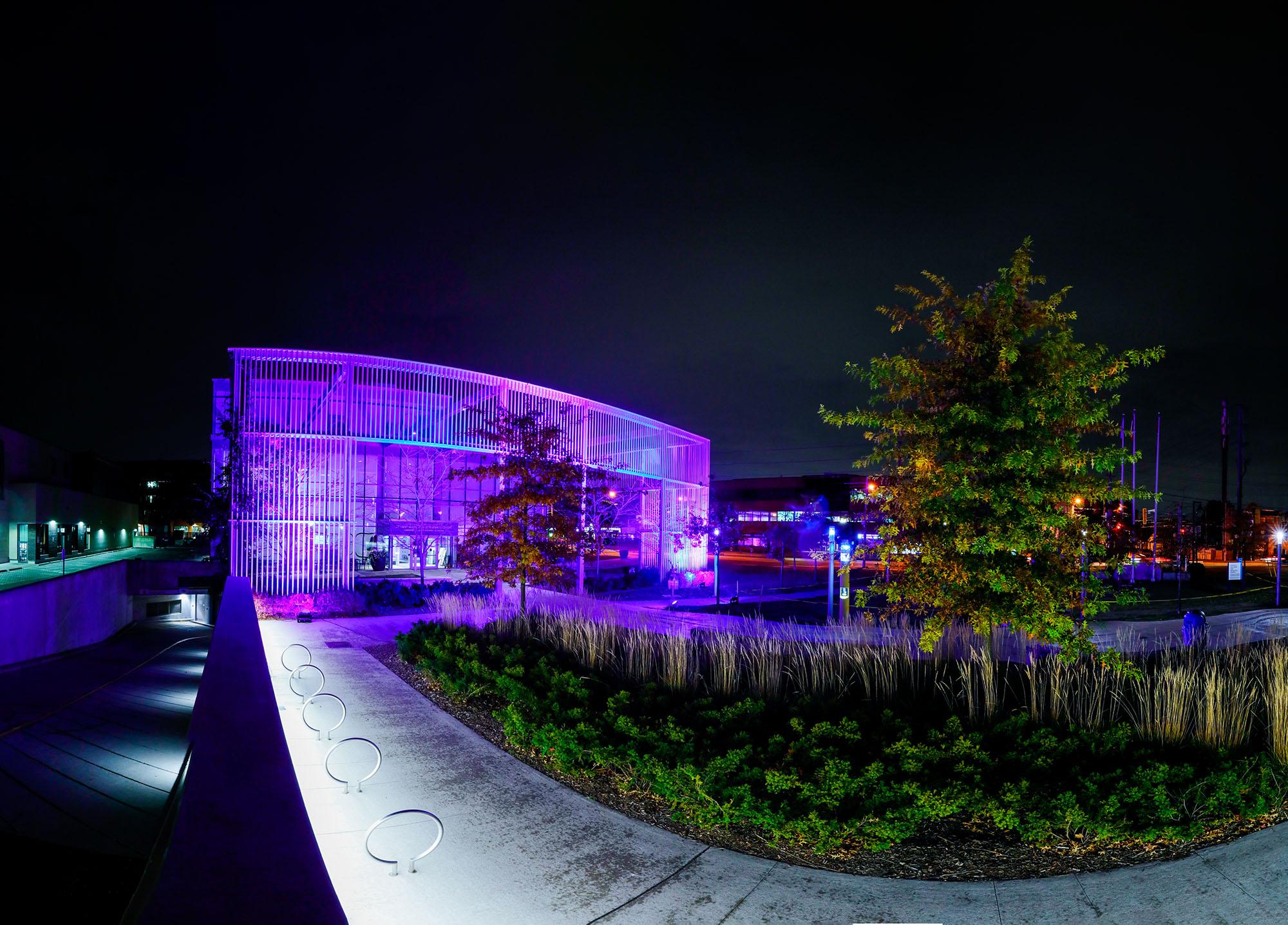 A photo of a building at night that has the colours blue and purple projected onto it.