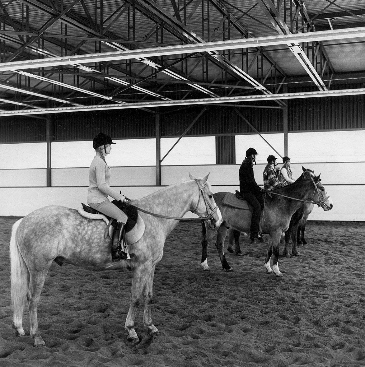 People in riding gear sit atop horses.