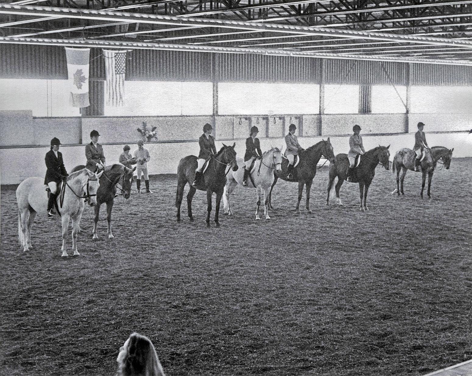 People in riding gear sit atop horses.