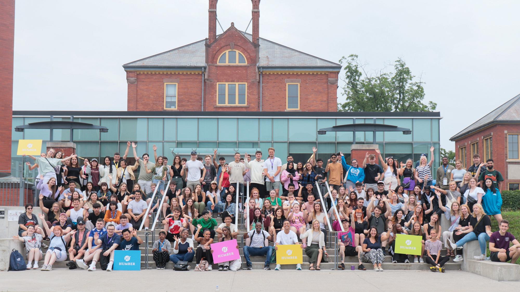 A large group of people sit on steps outside a building.