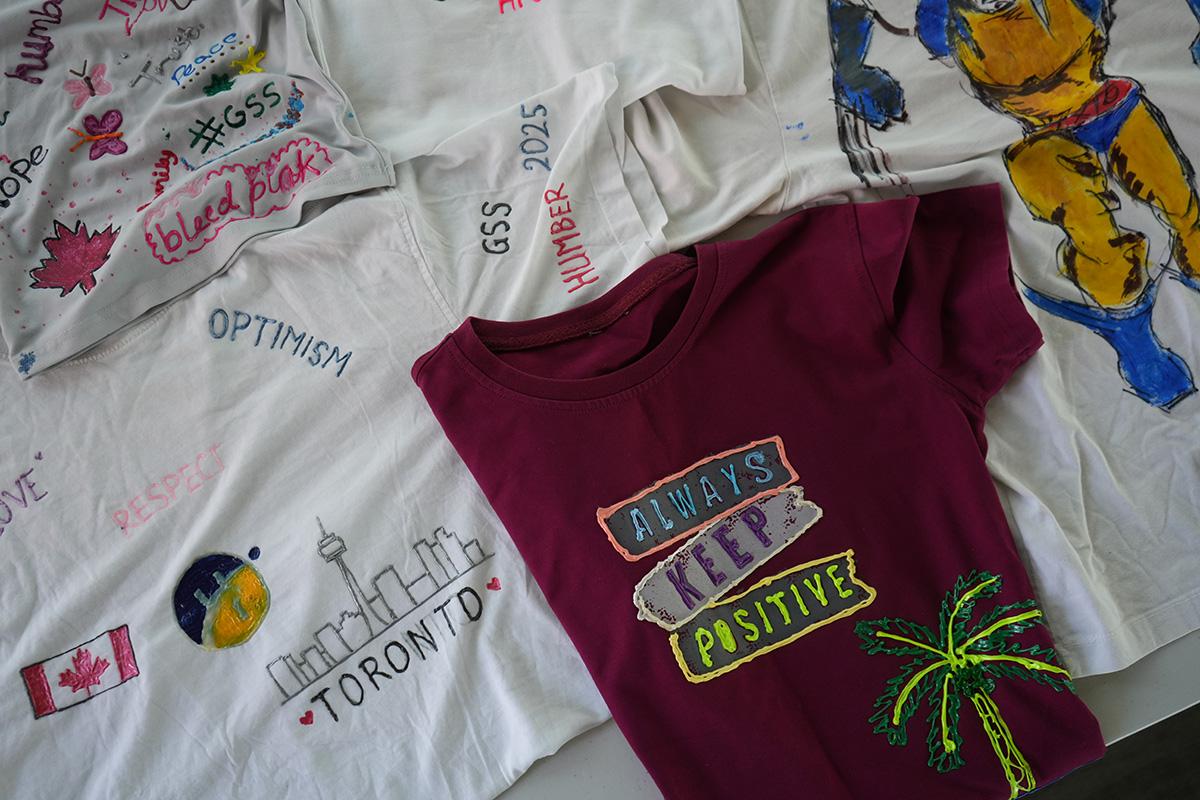 A series of t-shirts with designs on them are laid out on a table.
