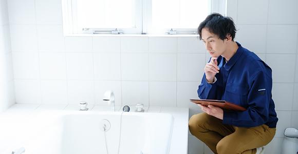 A person holding a clipboard is looking at a bathtub.