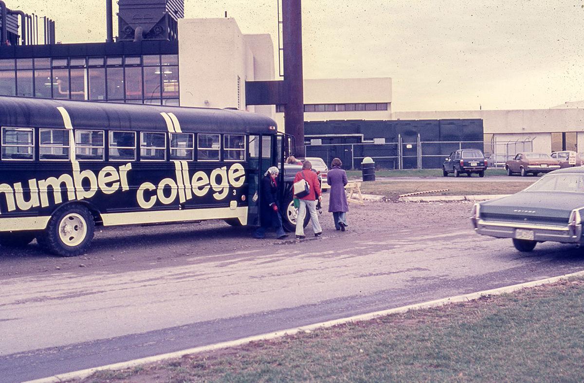 People board a bus with the words Humber College on it.