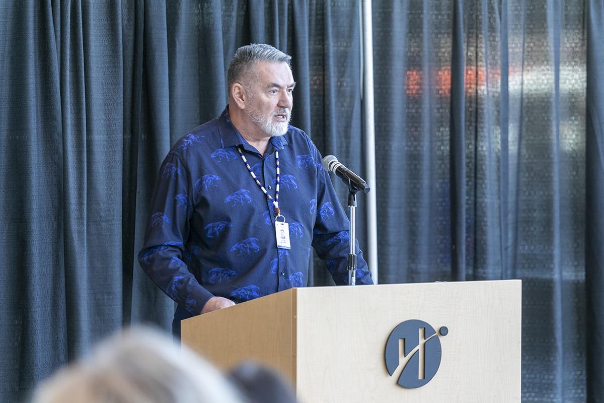 Humber Polytechnic has released its new Indigenous Education Plan – Biskaabiiyang: Returning to Ourselves, Reimagining the Future. A person is standing at a podium and is speaking into a microphone.