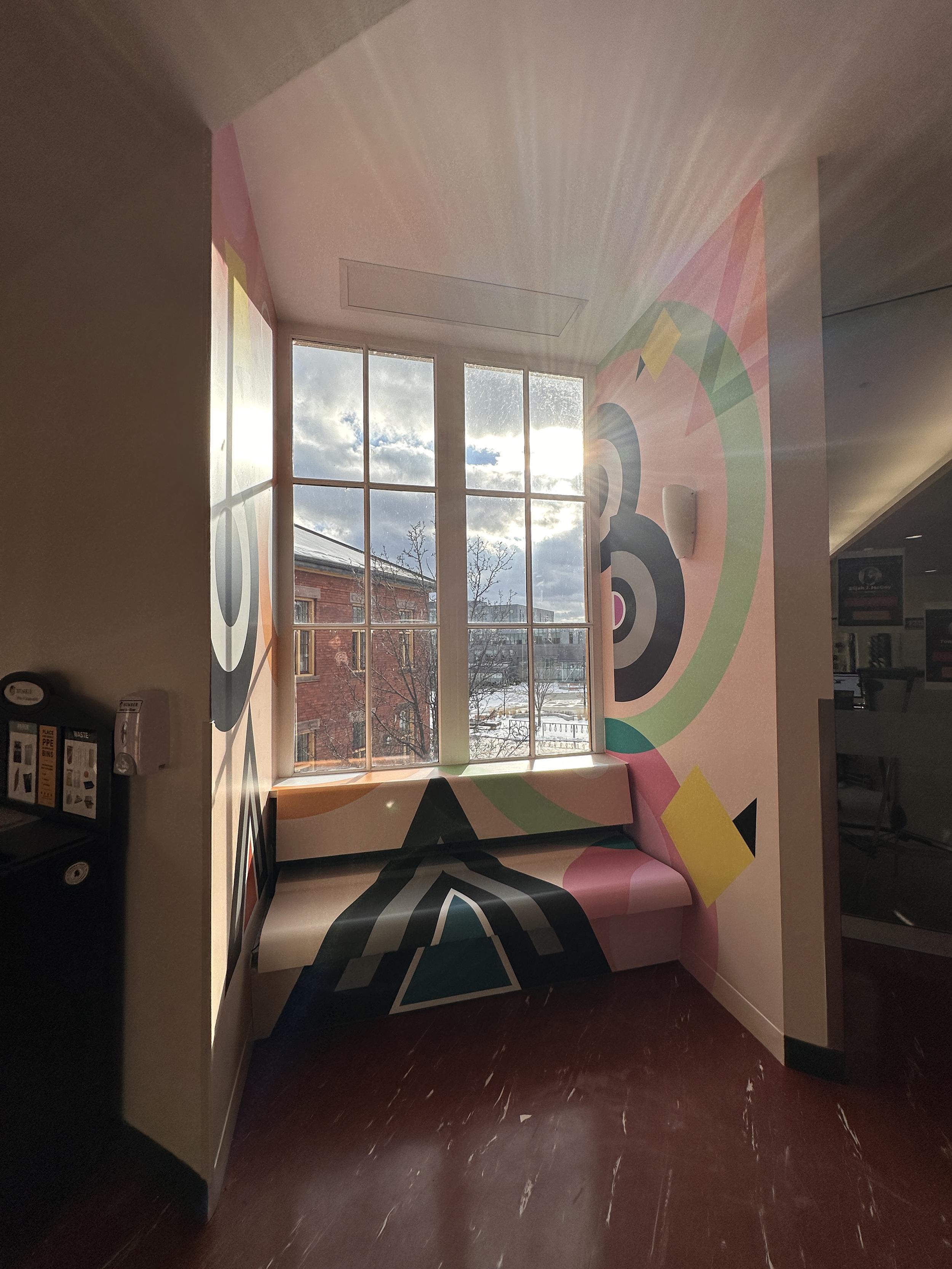 A mural is painted around a window, which is letting light in.