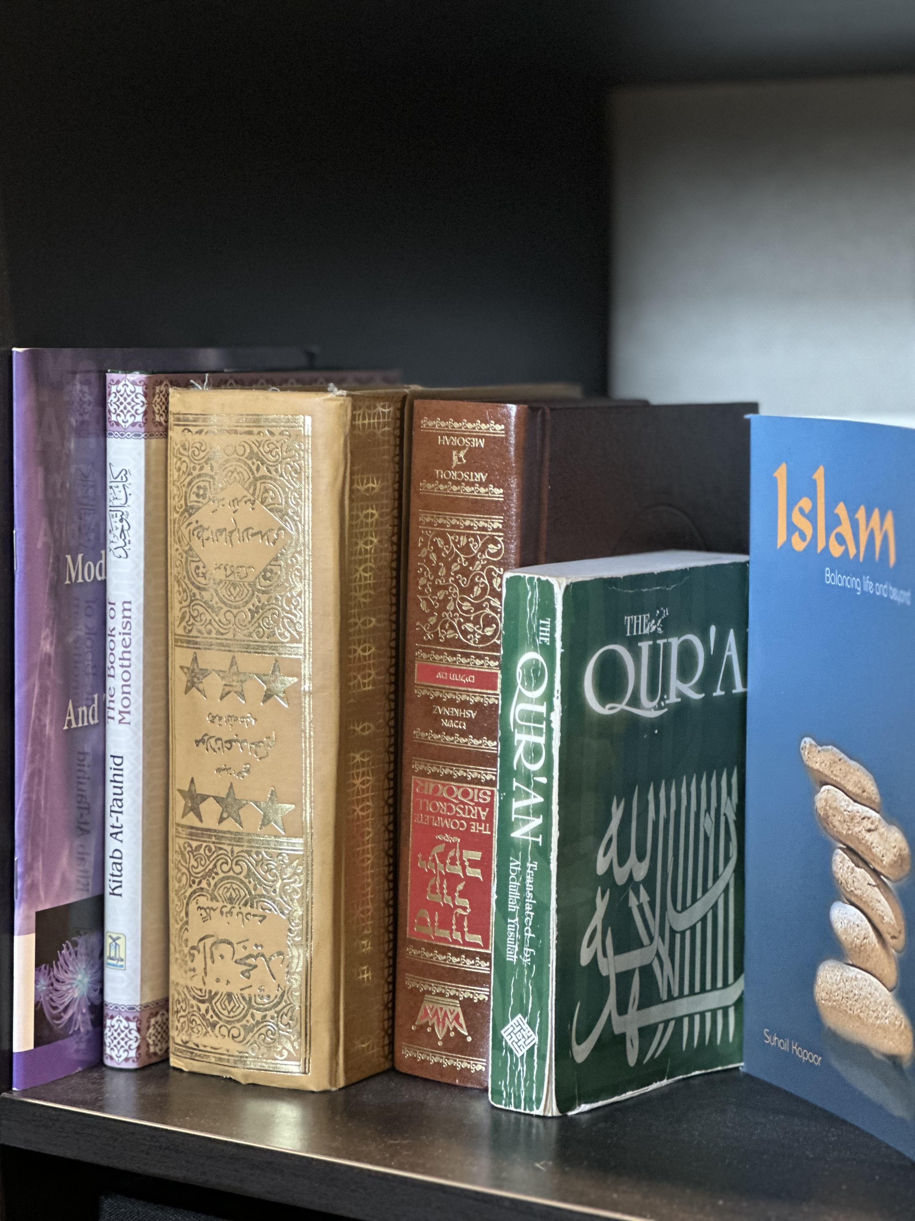 A series of religious books sit on a shelf.