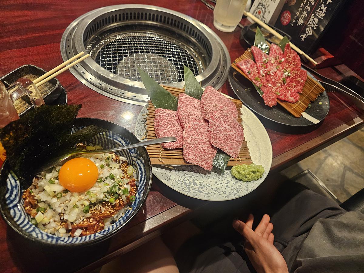 Various types of food sit on a table with a grill in the centre.