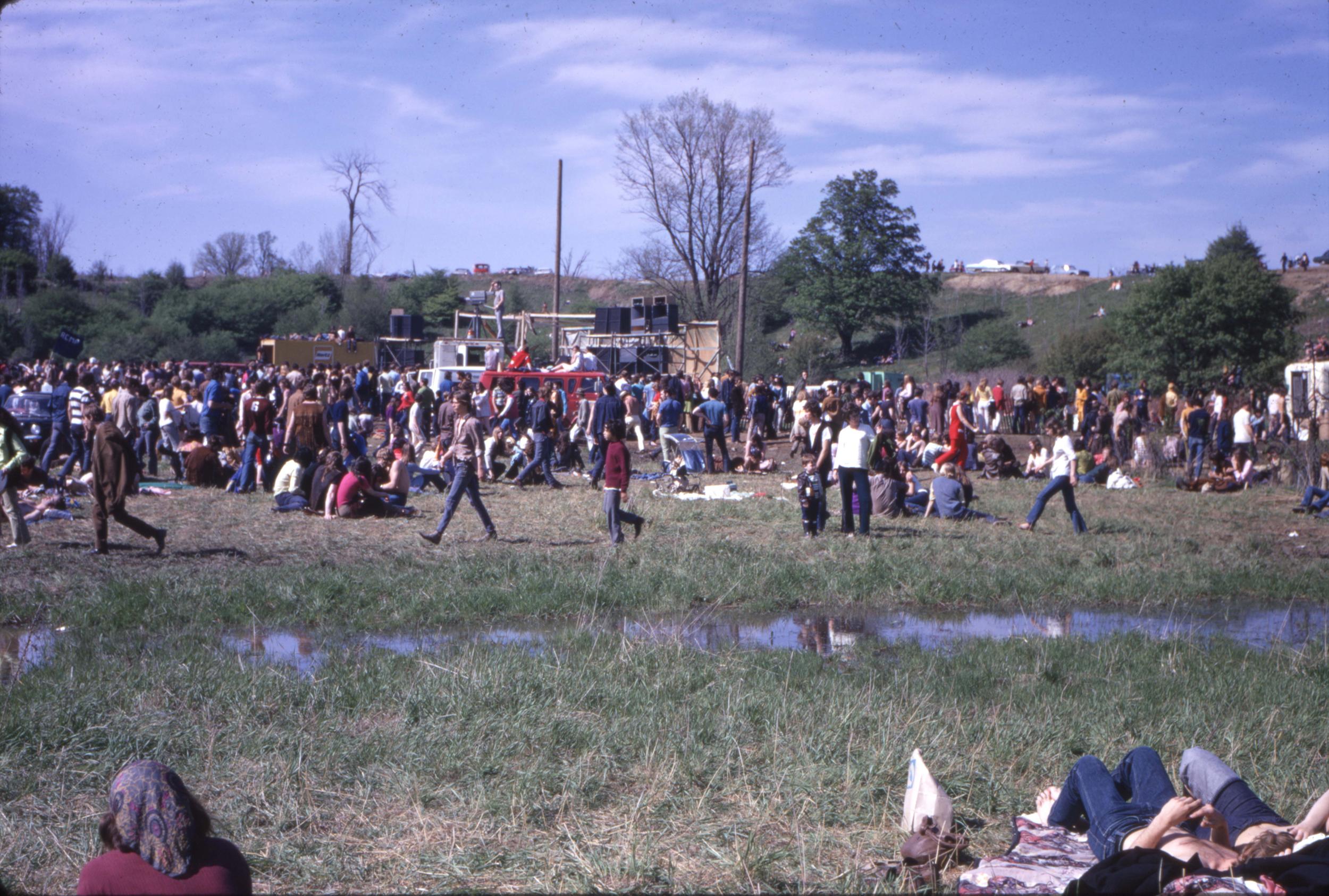 A group of people gathered around a stage that’s in the middle of a field.