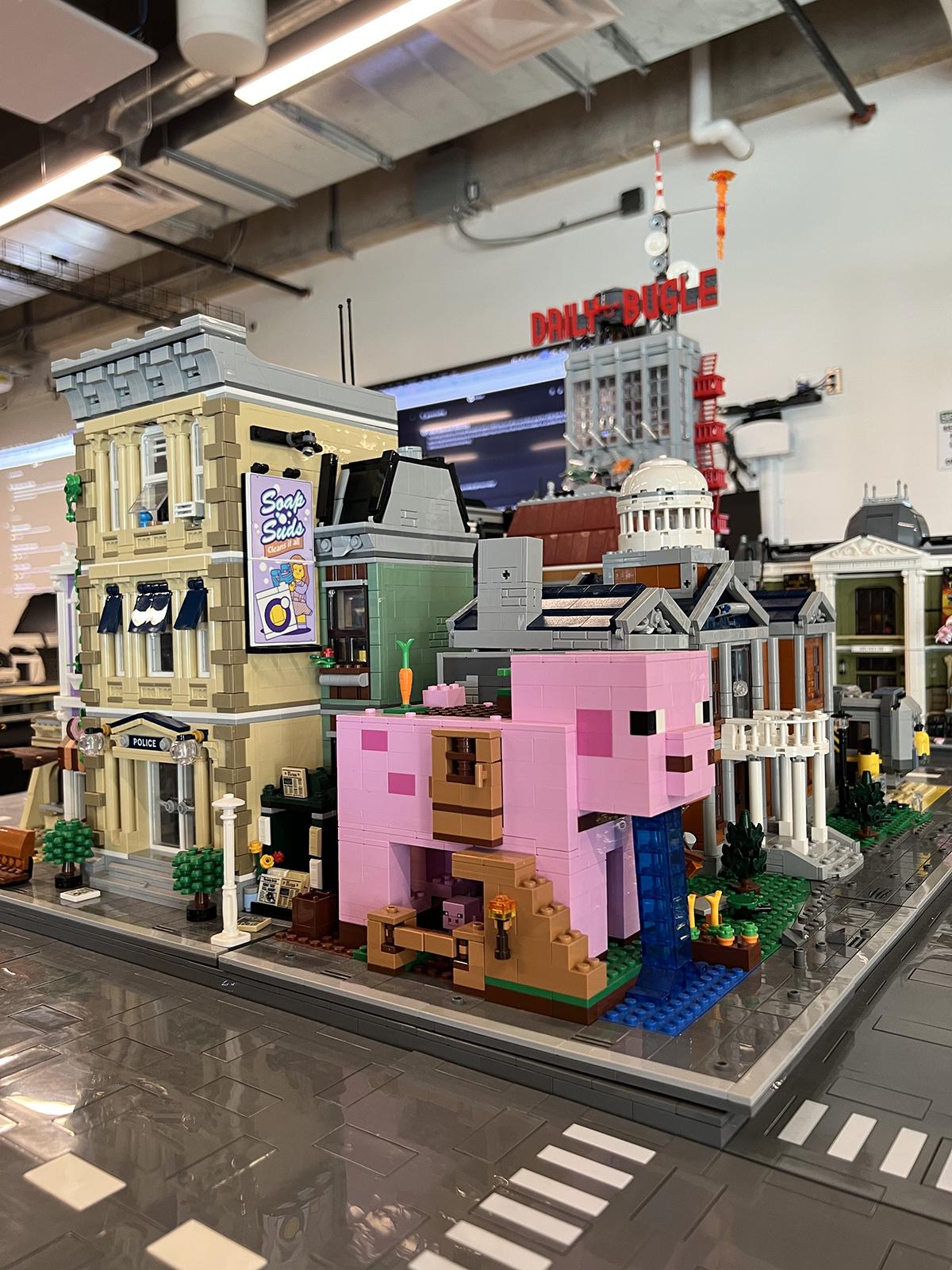 A series of buildings made of LEGO bricks. One building resembles a pink pig.