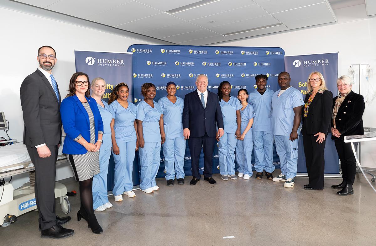 A group of smiling people stand together for a photo. Some are wearing medical scrubs.