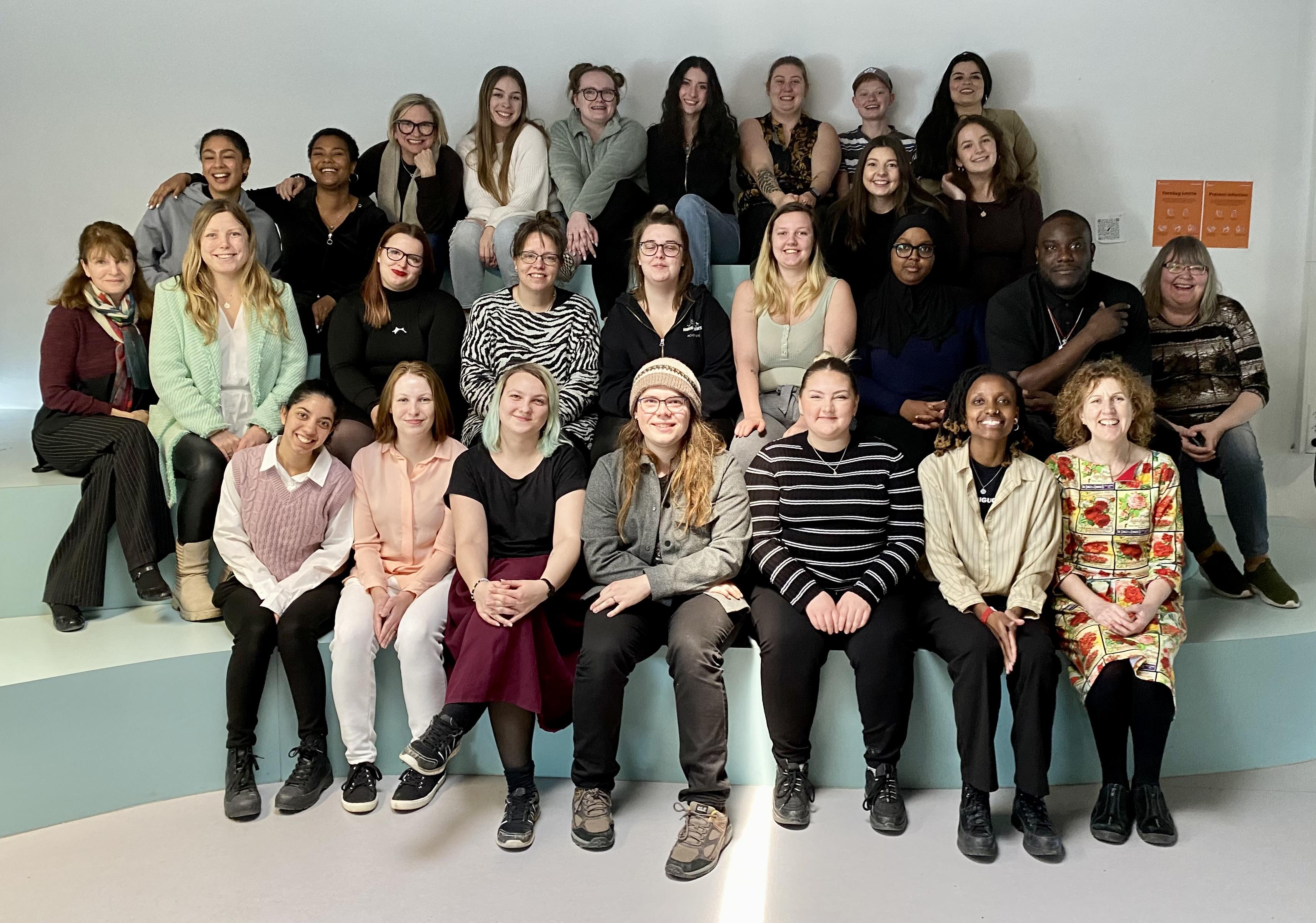 A large group of people sit in rows as they pose for a photo.