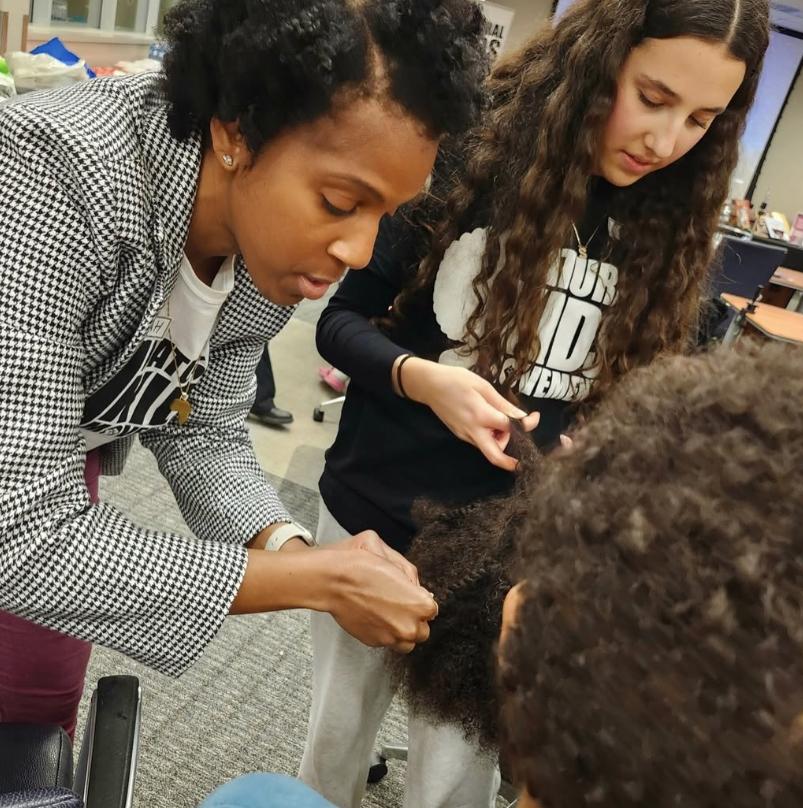 A person is working on another person’s hair.