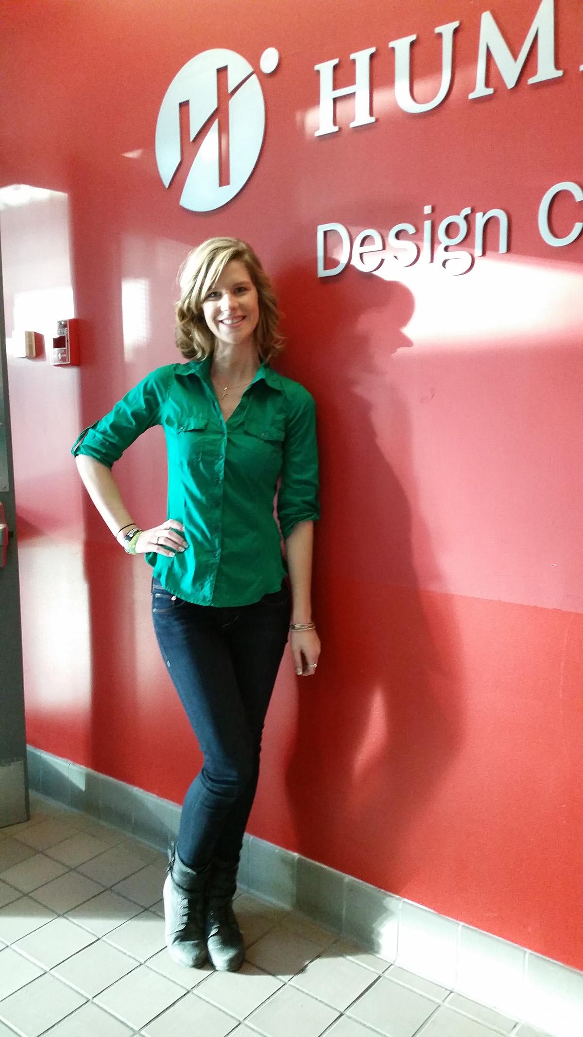 A person stands next to a red wall with the Humber Polytechnic logo on it.