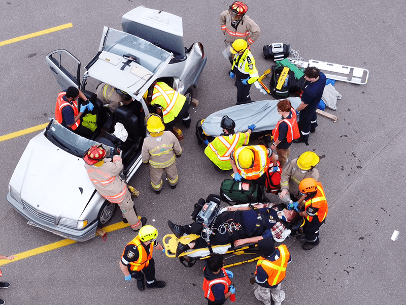 An overhead photo of students rescuing mock patients from a vehicle as part of a simulated mass casualty event.