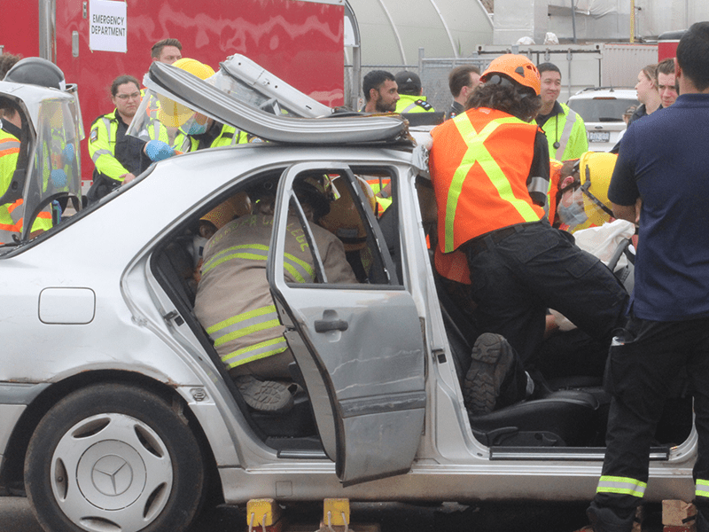 Students rescue mock patients from a vehicle as part of a simulated mass casualty event.