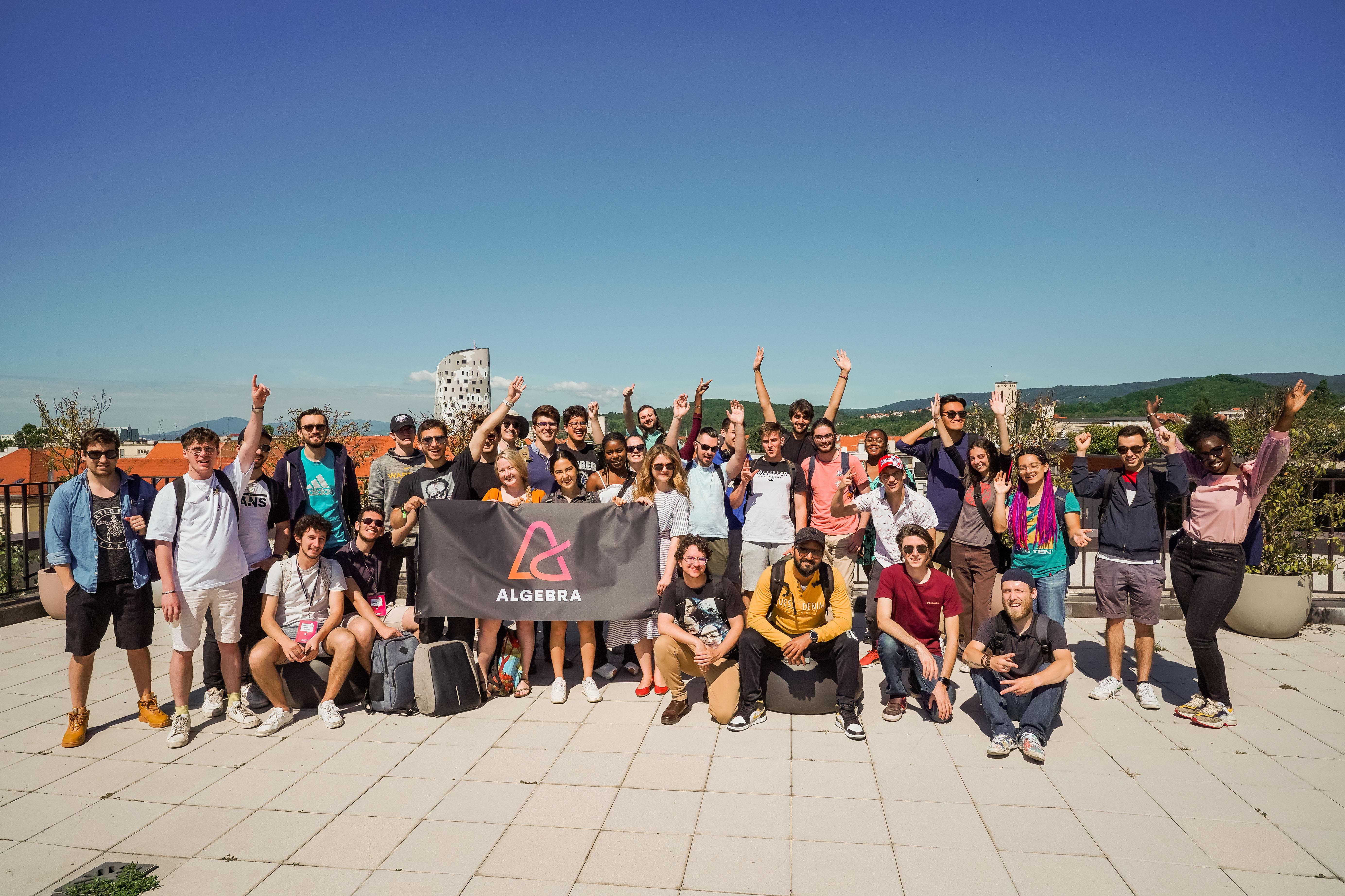 A large group of students pose for a photo while holding up a banner that reads Algebra.