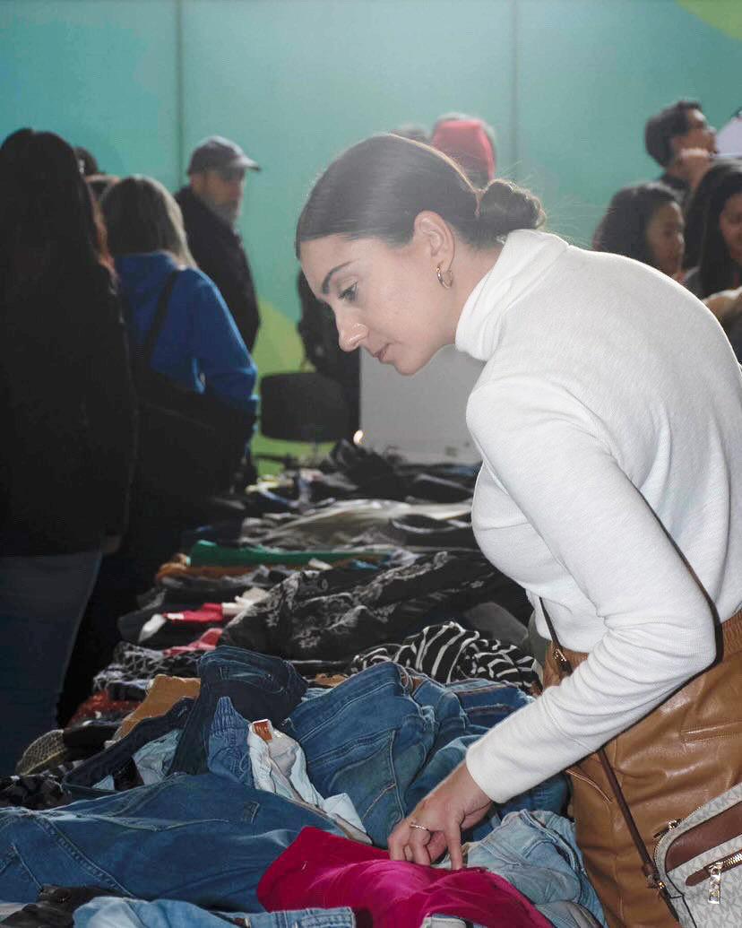 A person looks at some of the clothing that’s displayed on a table.