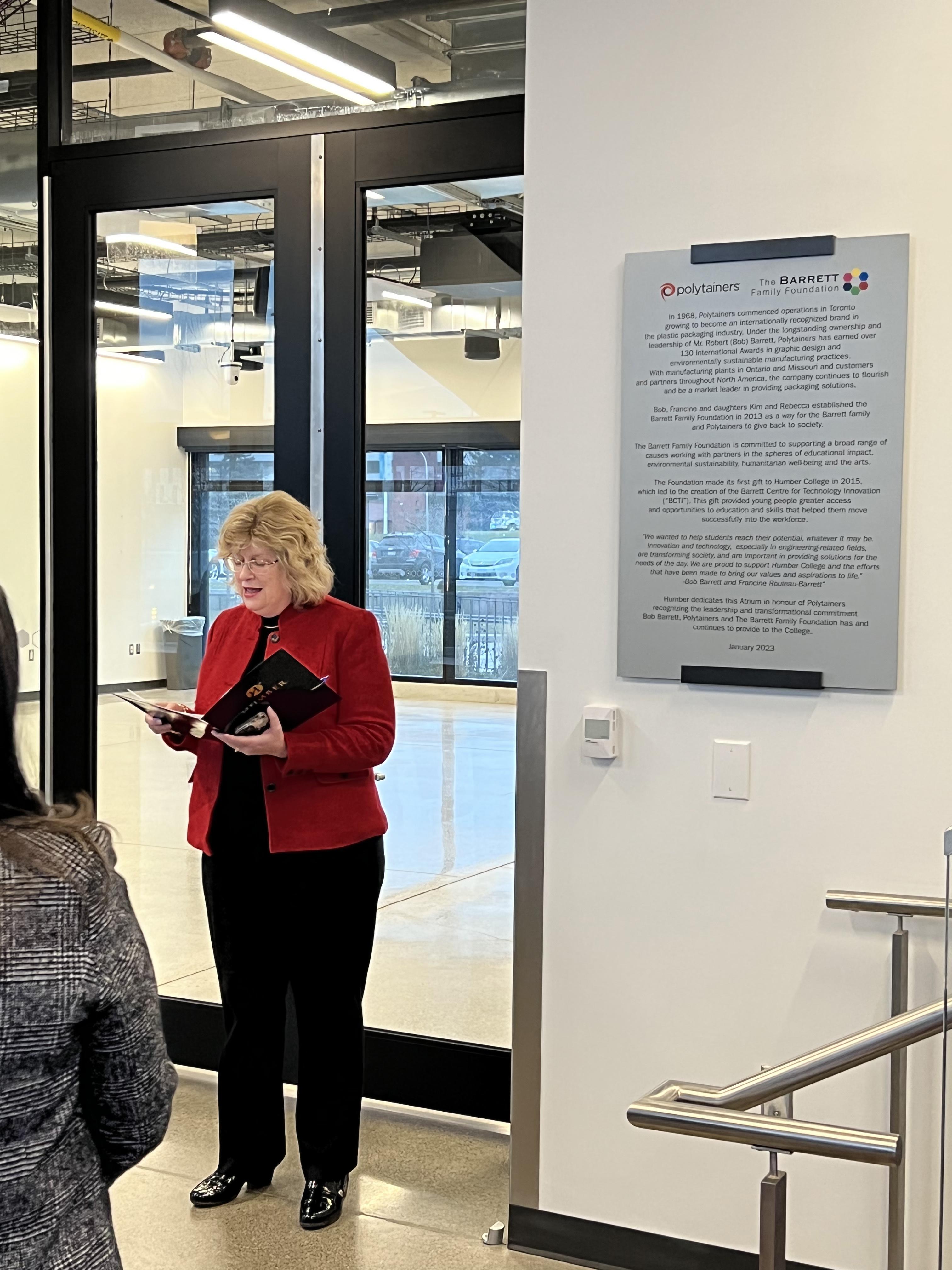 Humber’s president and CEO Dr. Ann Marie Vaughan reads from a speech while standing next to a plaque.