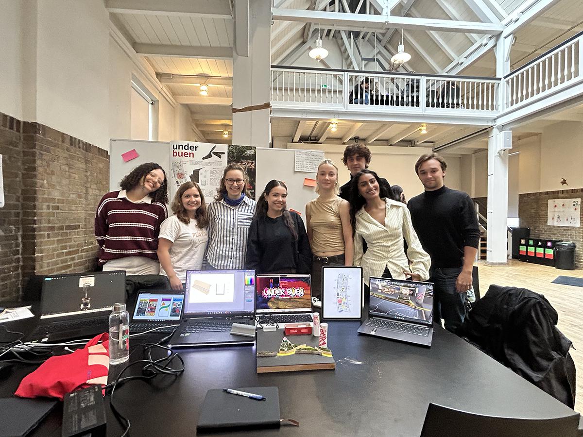 A group of people stand in front of a table that has information and displays on it for a presentation.