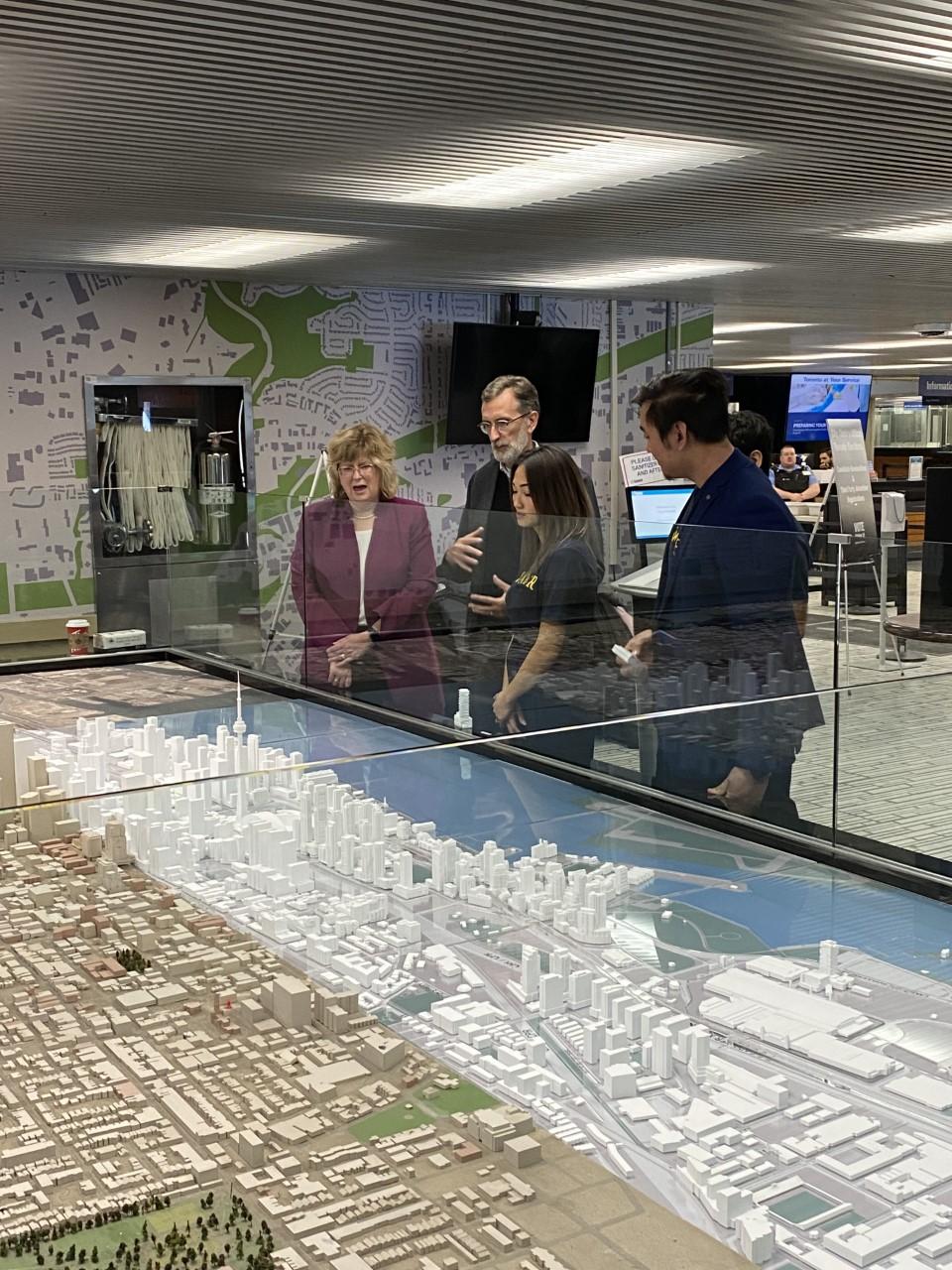 Several people, including three Humber College students, look at a model of the City of Toronto on display at City Hall.