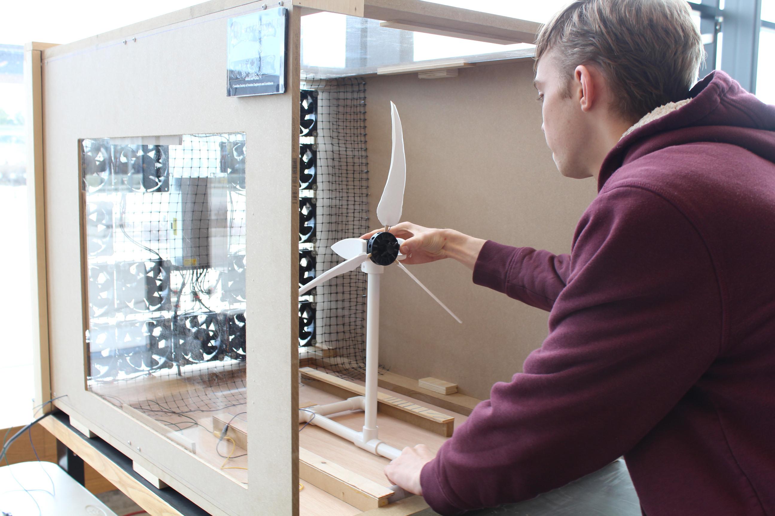 A person tests a wind turbine inside a wind tunnel.