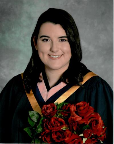Kayla Amaral poses for a graduation picture, holding roses and wearing a graduation collar/hood. She is smiling at the camera