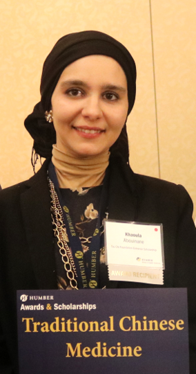 Khaoula Abouinane smiles, holding an award that says "Traditional Chinese Medicine"